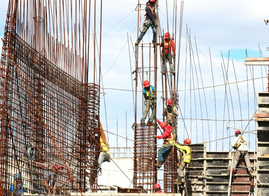 Construction workers on scaffolding installing rebar